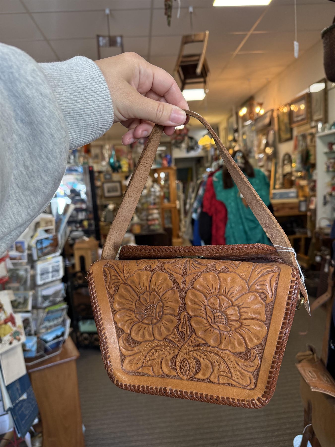 A tooled leather handbag held up in the aisle.